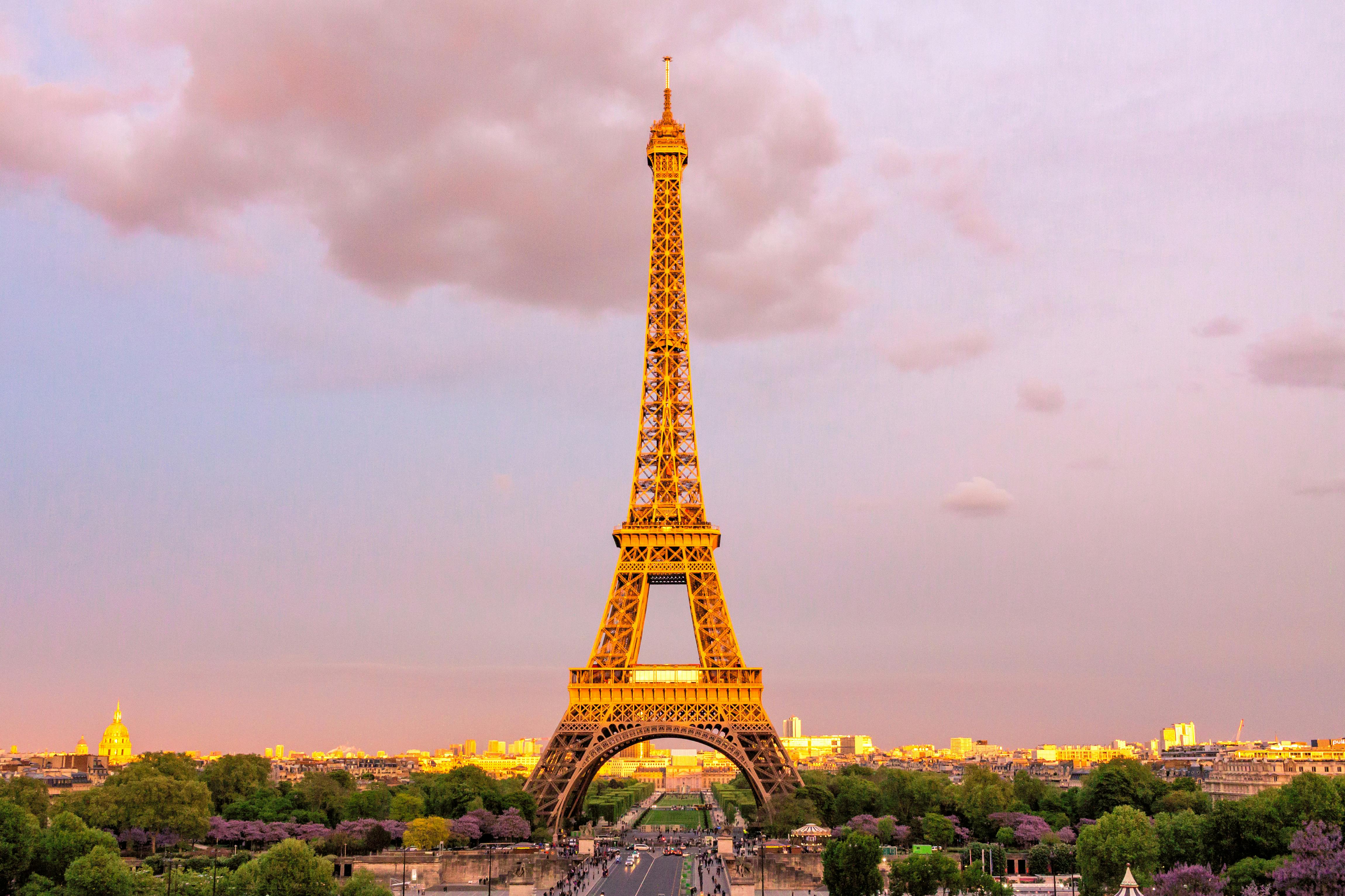 View of the Eiffel Tower in Paris, France against a sunset sky with pink hughes.